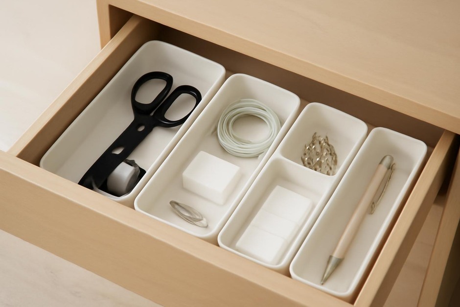 An open junk drawer with small organizers and neatly arranged items